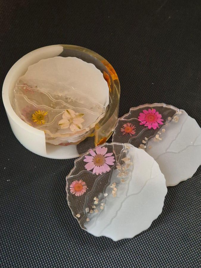 Round resin coasters with pressed flowers, stacked in a matching holder