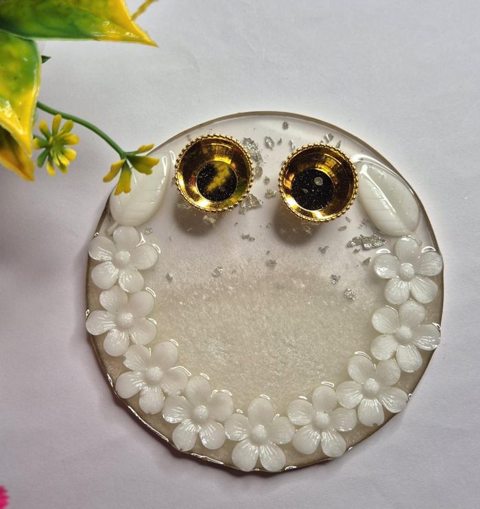 Round cream resin plate edged with white flowers, holding two gold tealight cups